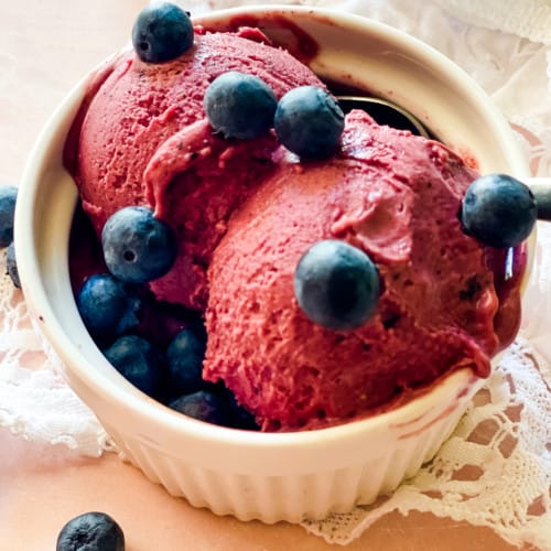 bowl of blueberry cheesecake ice cream with fresh blueberries on top