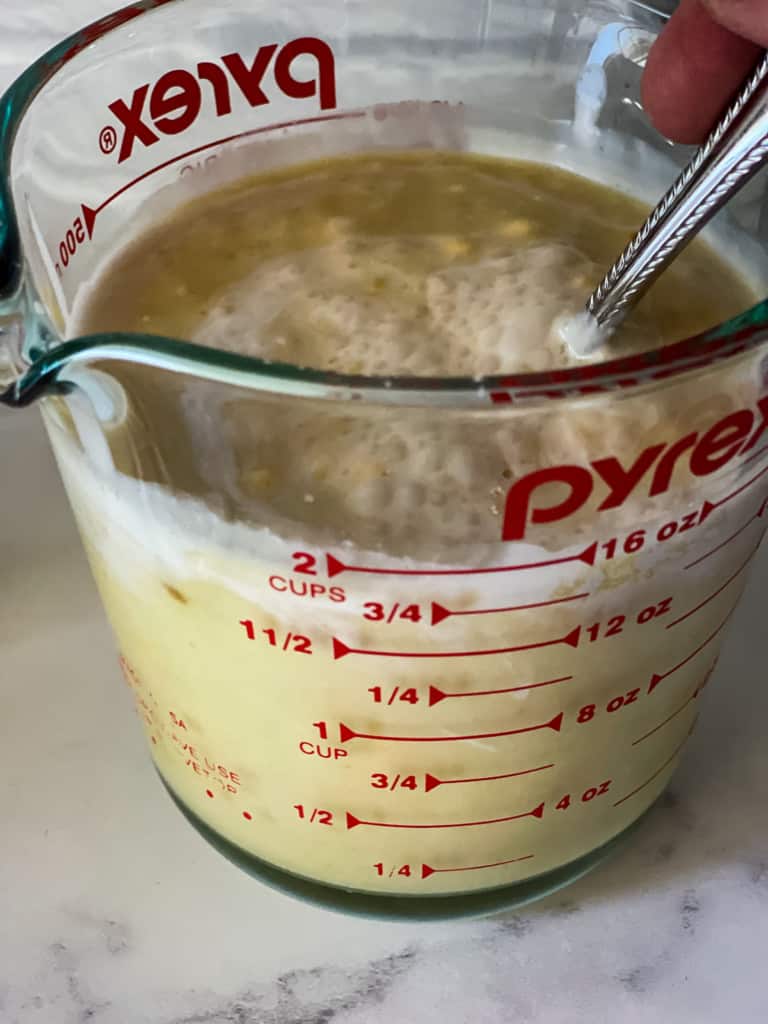 mixing the ingredients for orange creamsicle ice cream in glass measuring cup