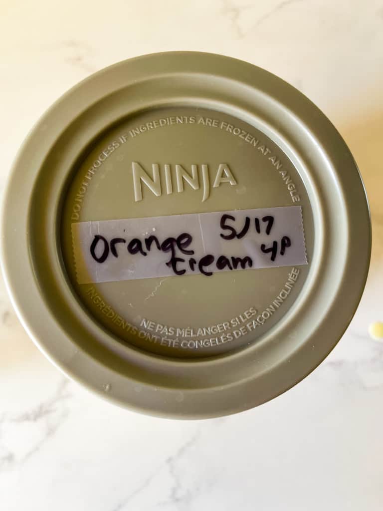 lid of Ninja Creami pint container with tape on top with information written on tape