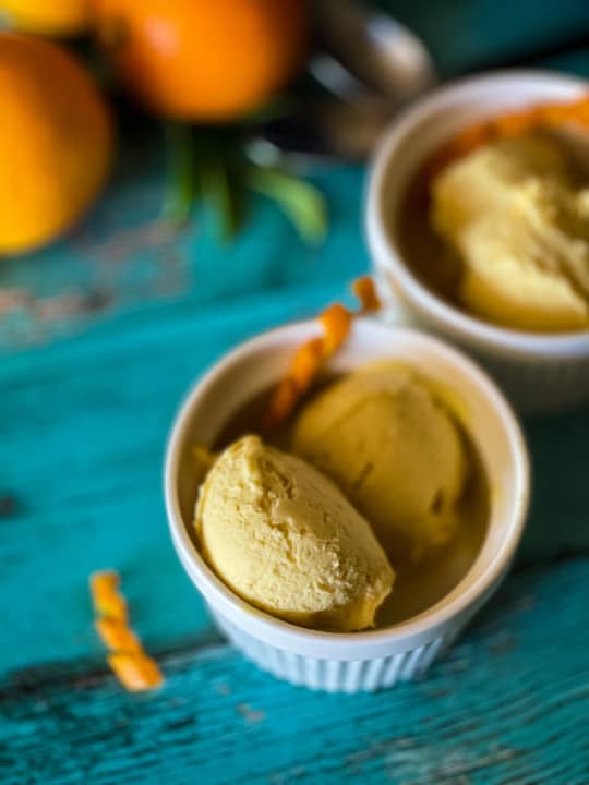 two bowls of orange creamsicle ice cream with oranges in background