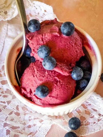 bowl of blueberry cheesecake ice cream with fresh blueberries on top