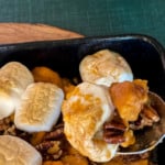 spooning out a portion of canned yams casserole with big marshmallow