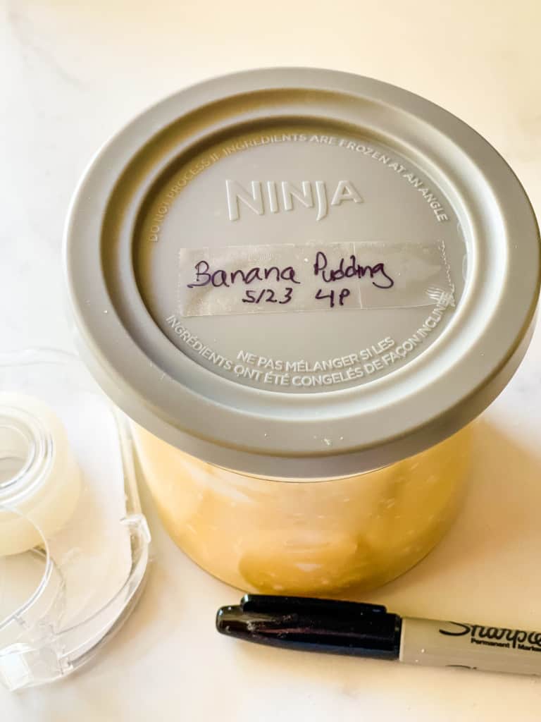 ninja container with lid on top written in sharpie the name of the recipe and the date with marker and tape in foreground
