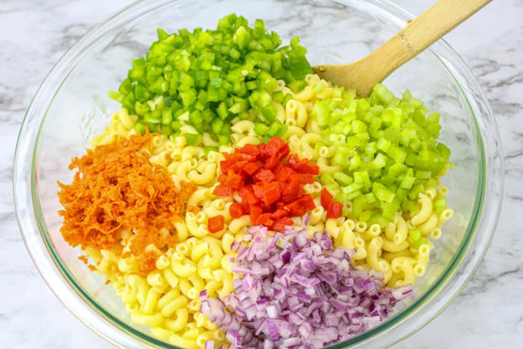 all of the ingredients for macaroni salad in glass bowl and ready to toss