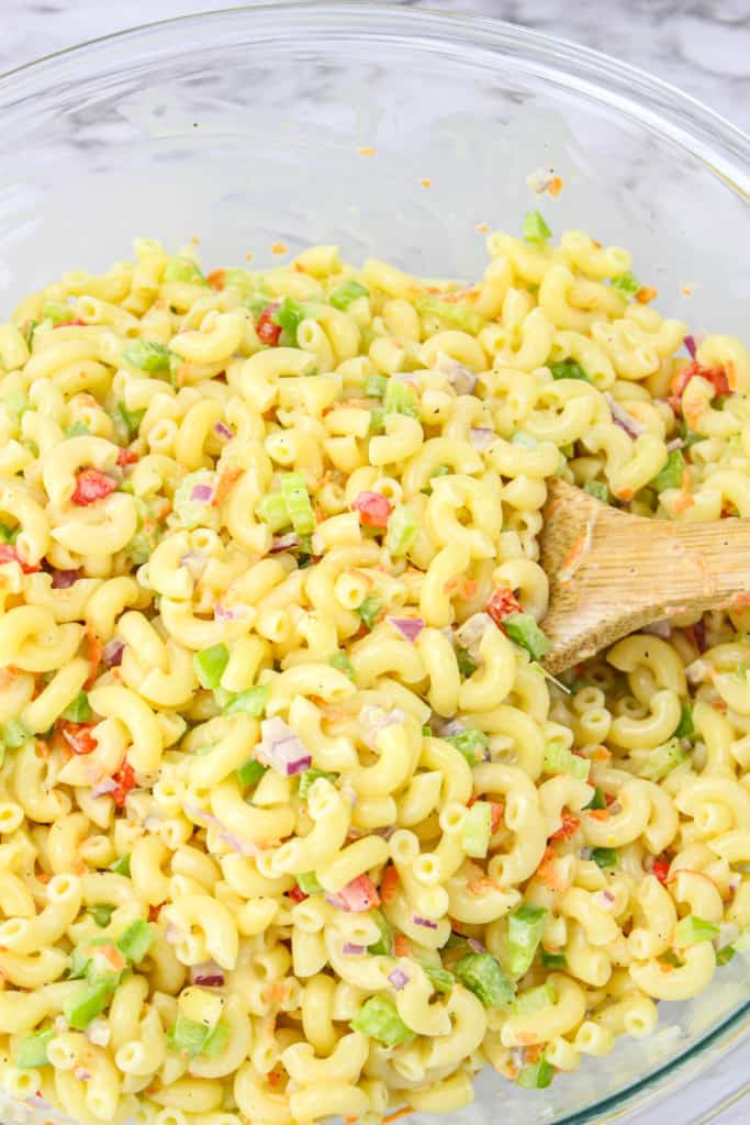 mixing together in vegan macaroni salad with a wooden spoon