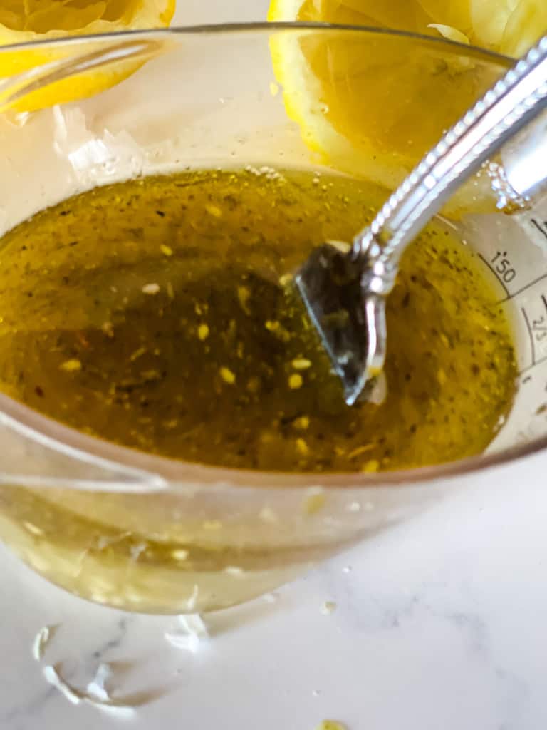 mixing the lemony dressing in measuring cup