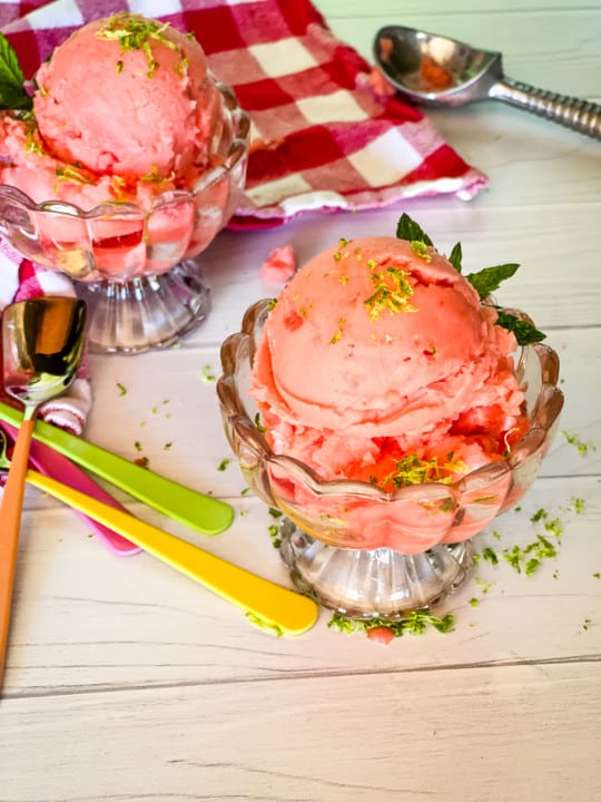 two dishes of watermelon ice cream with sprinkles of lime zest red checked napkin and ice cream scoop in background