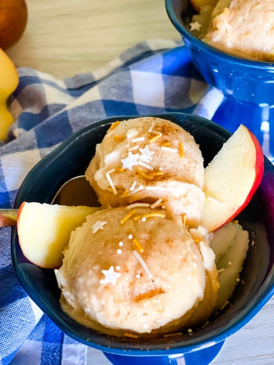 apple pie ice cream in two blue dishes with sprinkles on top and apple slices on the side