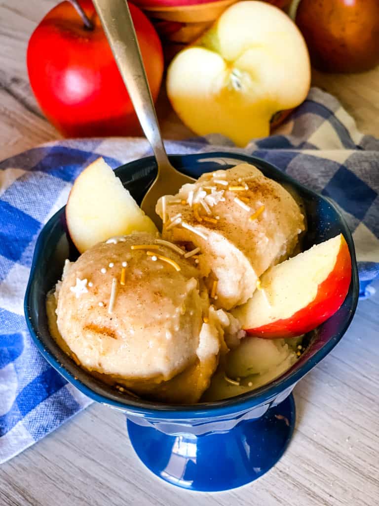 apple pie ice cream in blue dish with sprinkles on top and apple slices on the side