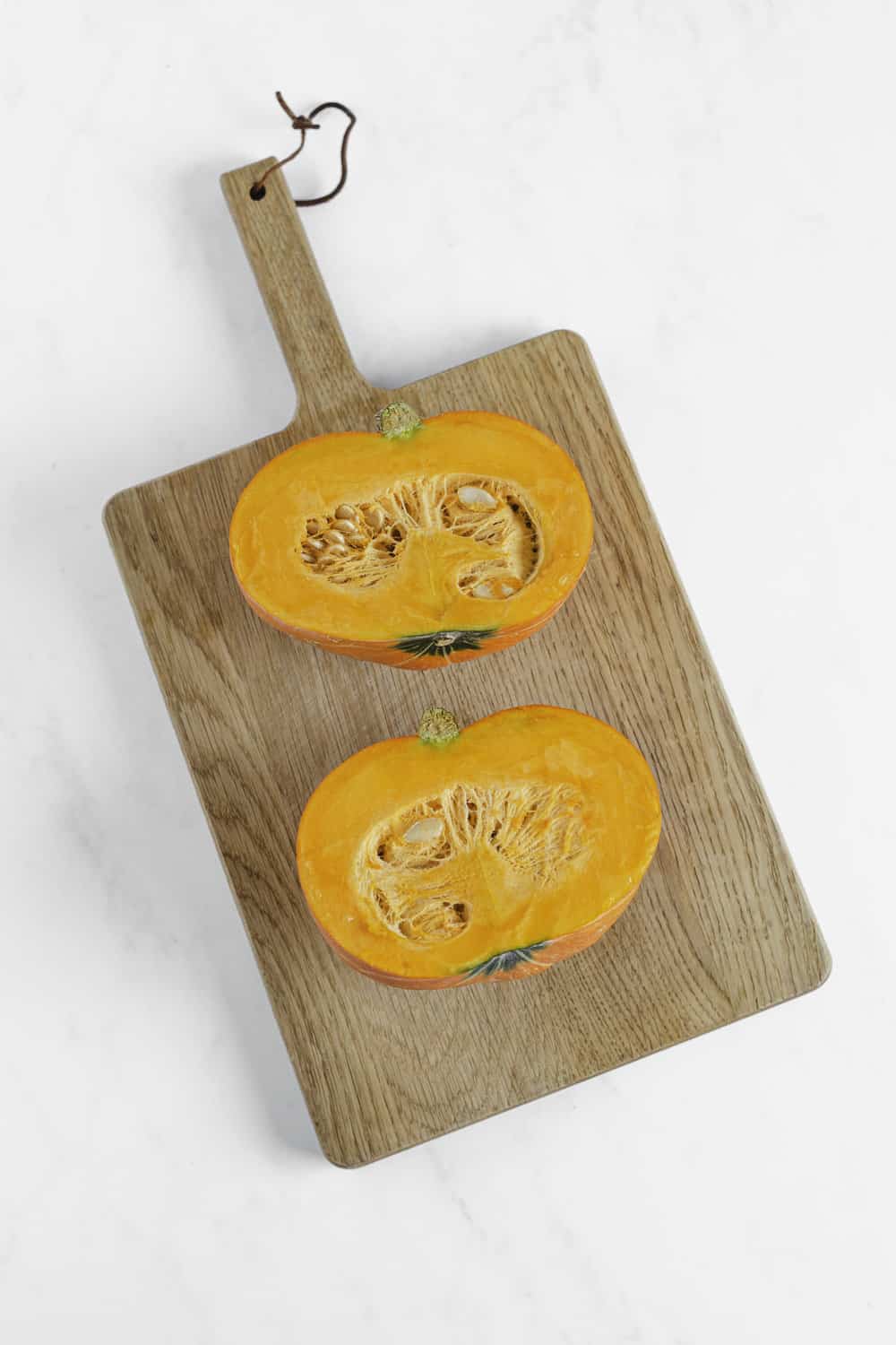 two pumpkin halves on cutting board