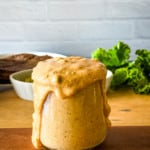 overflowing jar of vegan burger sauce with burgers and lettuce in the background