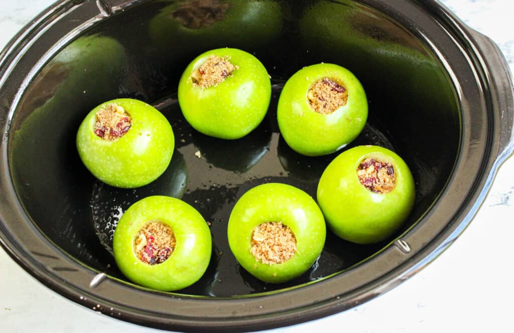cored apples in a crockpot with filling