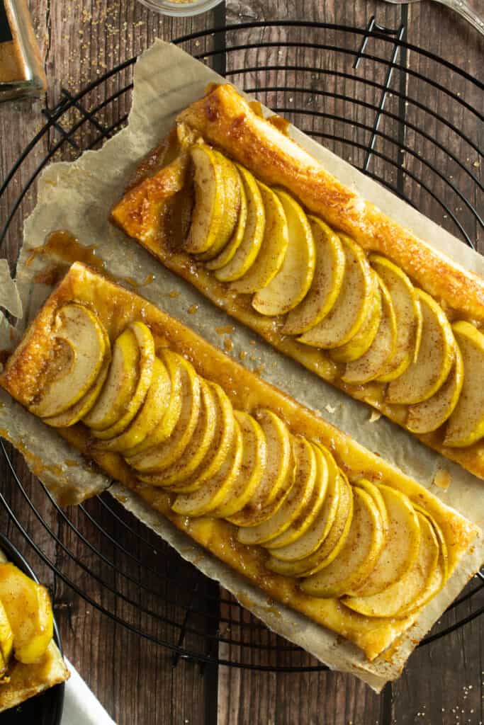 two apple tarts on a parchment paper without drizzled caramel
