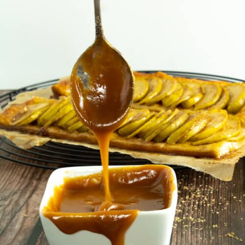 caramel drizzled in foreground with apple tart in background