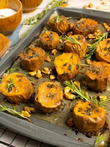 sweet potato rounds on baking sheet with fork in corner with rosemary