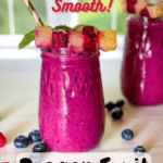 two glasses of dragon fruit smoothies with garish on top and berries scattered around with pinterest text overlay