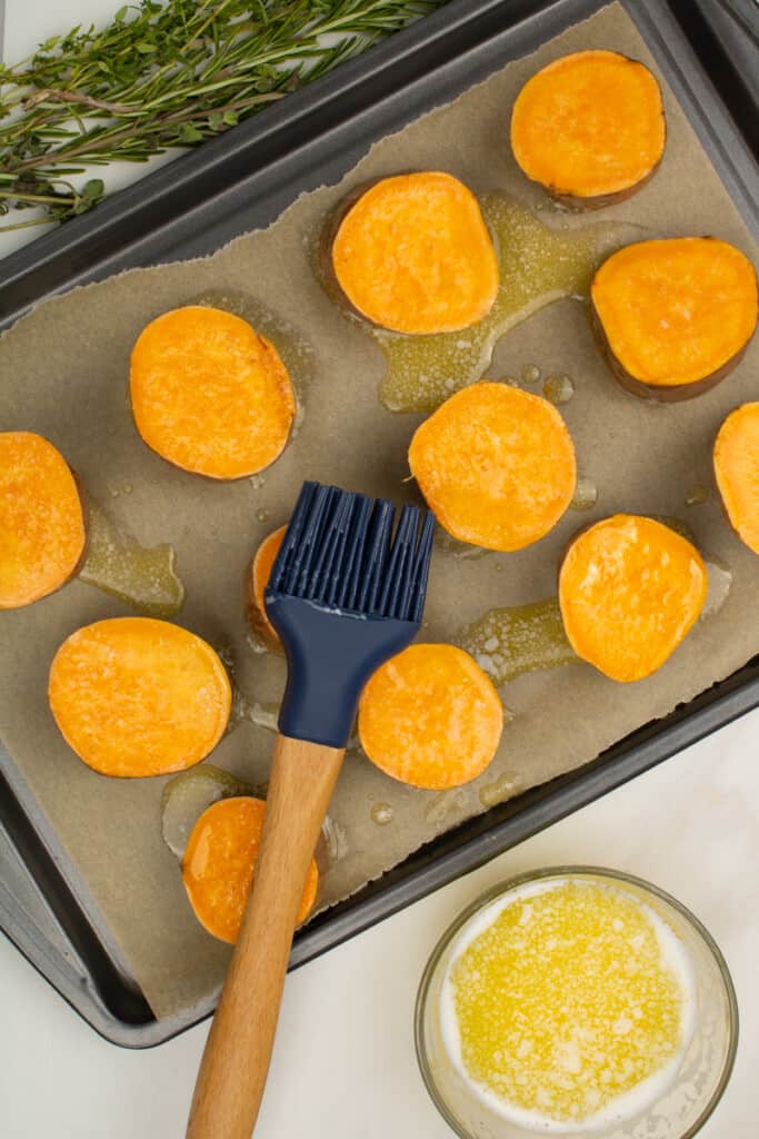 adding melted butter to sweet potato rounds