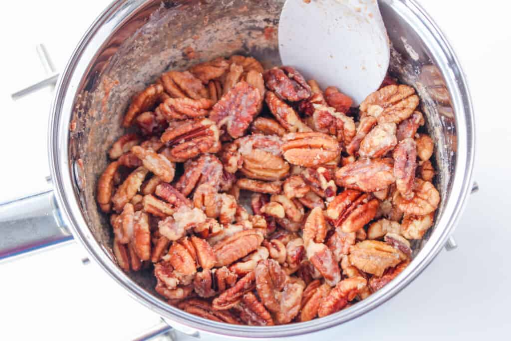 stirring the candied pecans in a metal pan