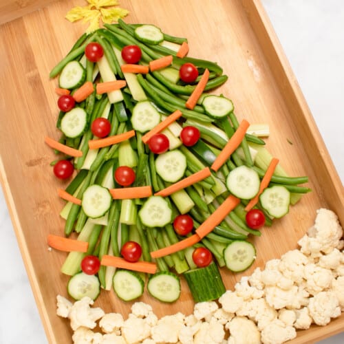 vegetable christmas tree appetizer on wooden board with christmas greenery in background