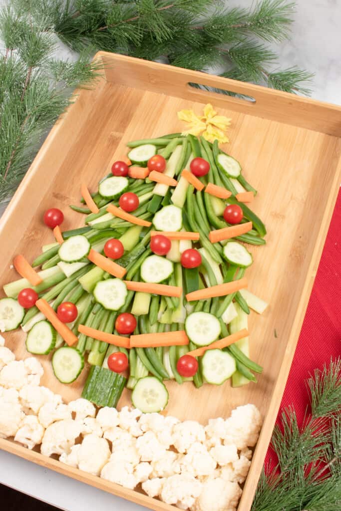 vegetable christmas tree appetizer on wooden board with christmas greenery in background