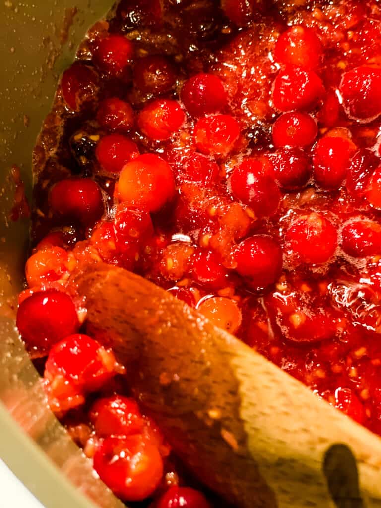 mashing the cranberries against the side of the pan