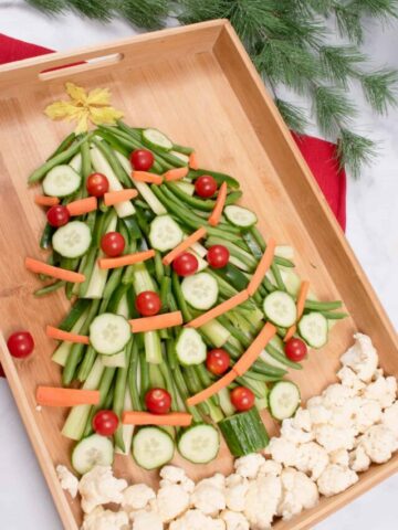 vegetable christmas tree appetizer on wooden board with christmas greenery in background