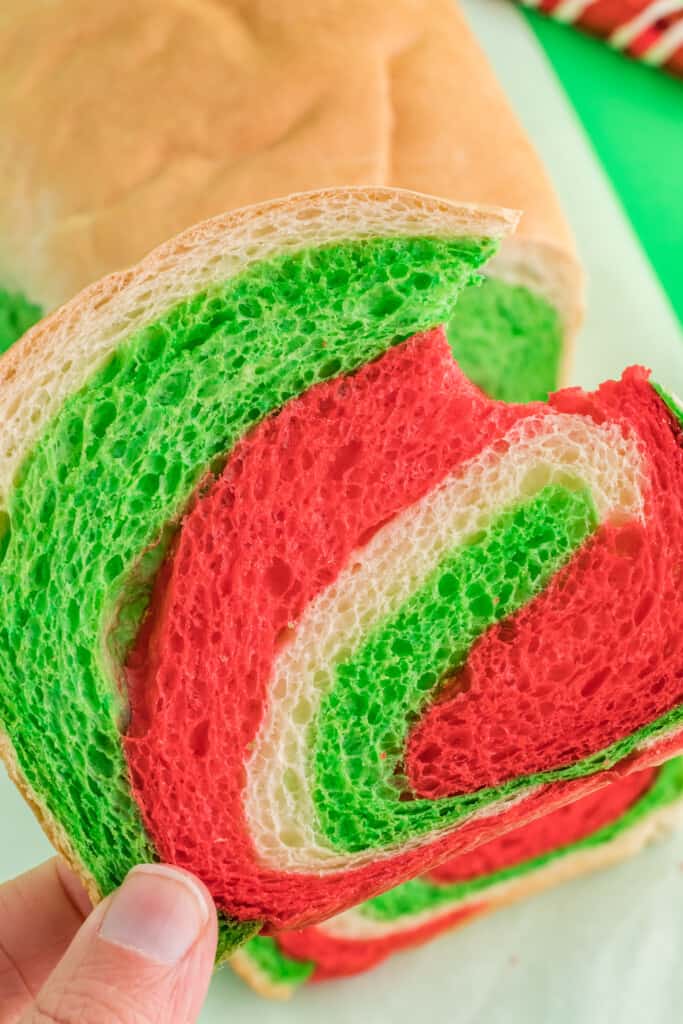 holding a slice of christmas swirl bread with a bite taken from it