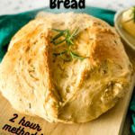 round loaf of rosemary garlic bread on a bread board with pinterest text overlay