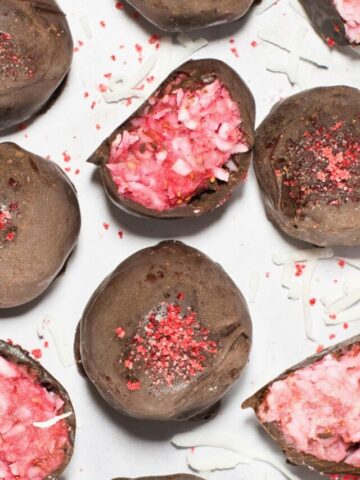 12 chocolate dipped truffles on parchment and one with bite out in foreground.