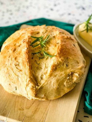 round loaf of rosemary garlic bread on a bread board