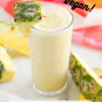 glass of orange pineapple smoothie with cut pineapple chunks to garnish. And orange and pink background. With pinterest text overlay