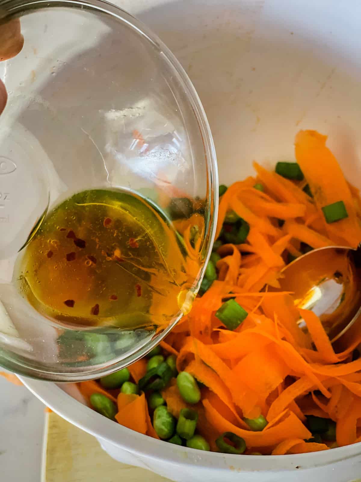 pouring dressing in raw carrot salad