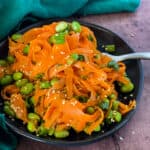plated raw carrot salad with edamame with some on fork