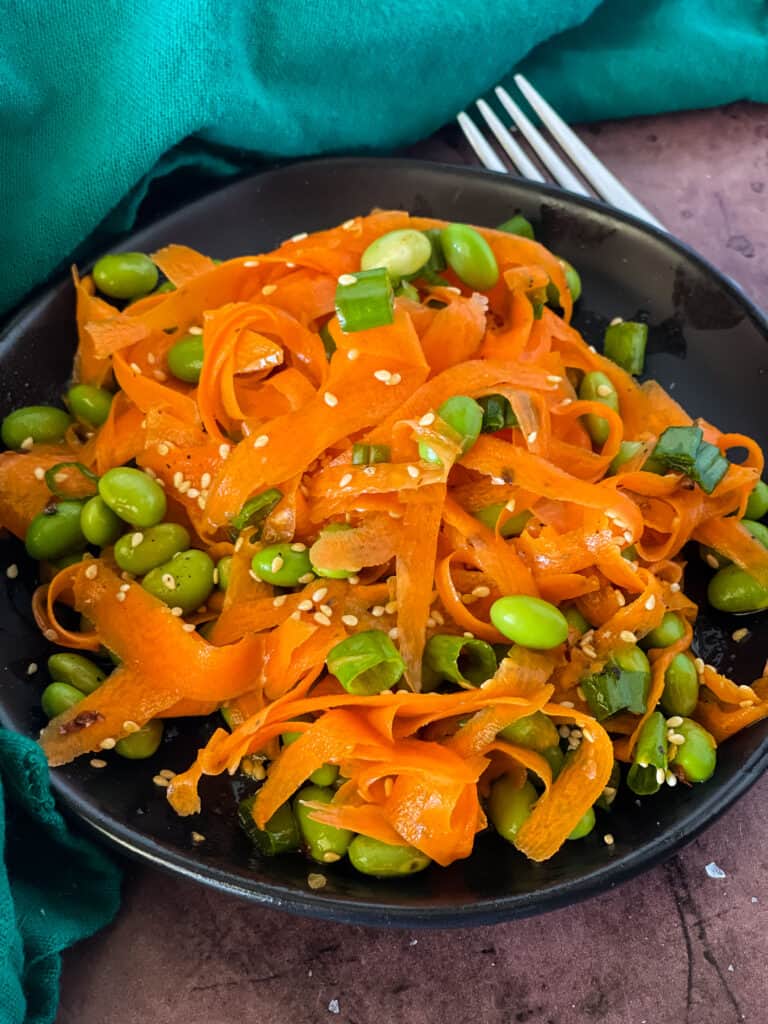 plated raw carrot salad with edamame with fork on right