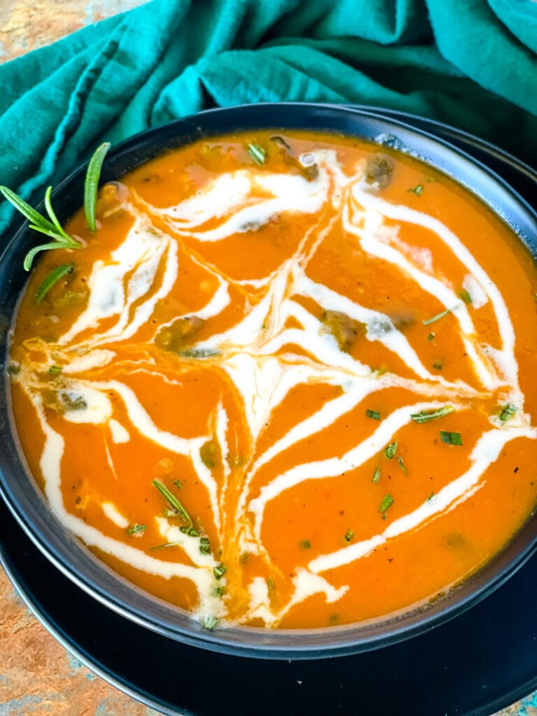 bowl of butternut squash red pepper soup with coconut lime cream drizzle on top