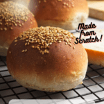vegan burger buns with sesame seeds on a wire rack with Pinterest text overlay.