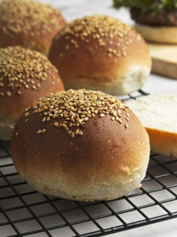 closeup of baked hamburger buns on a wire rack.