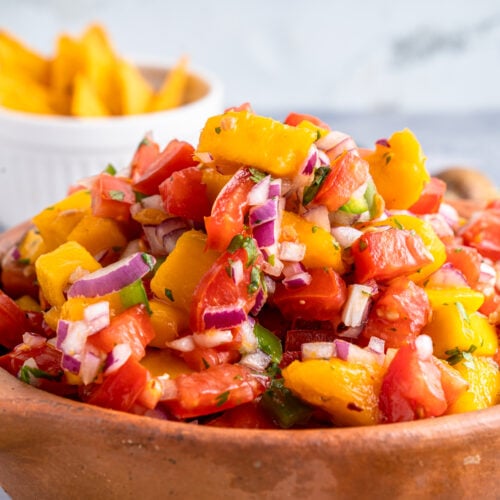 bowl of mango pico de gallo with chips in background