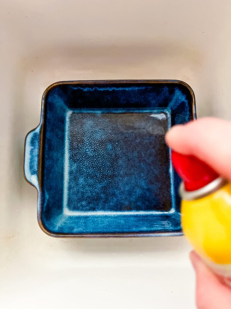 Showing cooking spray on a blue baking pan in the sink to avoid an oily mess.
