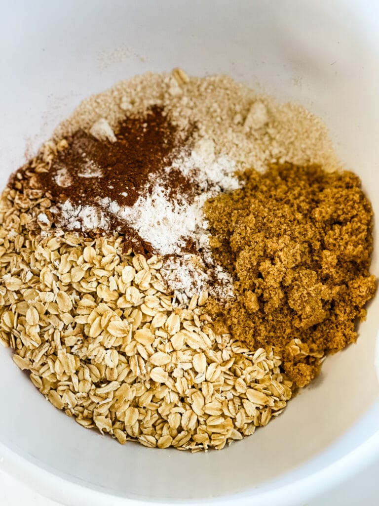 Adding the dry ingredients to a bowl. The oats, oat flour, brown sugar, baking soda, and cinnamon.