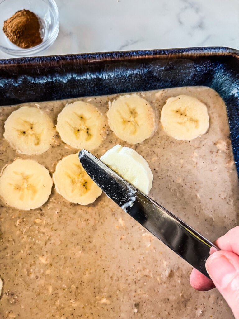 Slicing bananas and adding to the top of the unbaked oats.