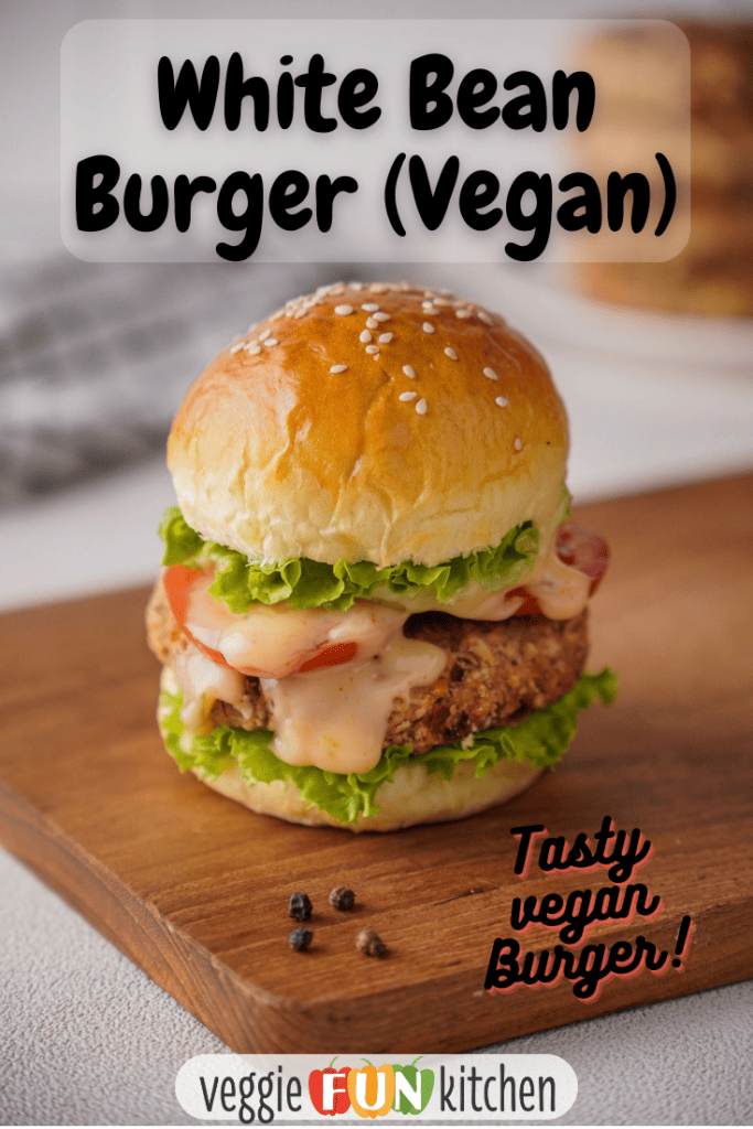 White bean burger on a bun with lettuce, tomato and vegan burger sauce. Sitting on a wooden cutting board with pinterest text overlay.