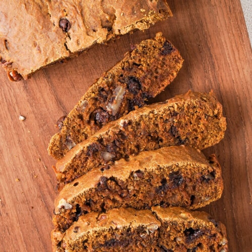slices of pumpkin bread with chocolate chips on a bread board.