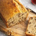 sliced maple walnut bread and some of the whole loaf on a wooden cutting board.