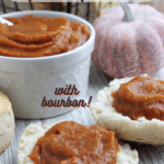 White bowl with pumpkin butter. Two biscuit halves with a generous helping of pumpkin butter spread on each with a ceramic pumpkin prop to the right. WIth pinterest text overlay.