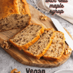 Slices of maple walnut bread on a wooden platter with the rest of the loaf behind it. A bottle of maple syrup in the background. With pinterest text overlay.