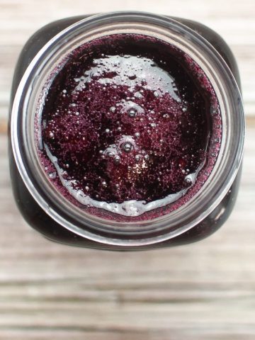 Top view of blackberry jam showing a small amount of berry foam on the top of the jar.