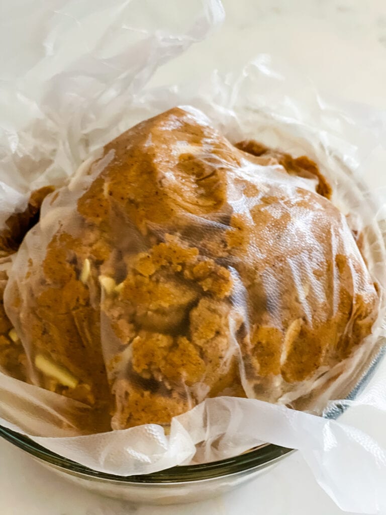 A almond butter cookie dough ball covered with plastic wrap ready to chill.