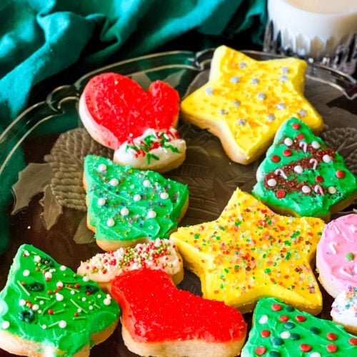 Christmas cookies decorated with buttercream icing including four trees, two stars, one mitten and one stocking.