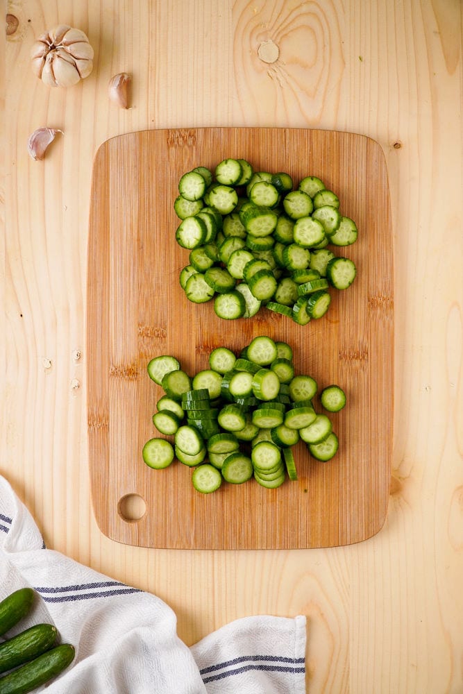 Sliced cucumbers on a wooden cutting board.